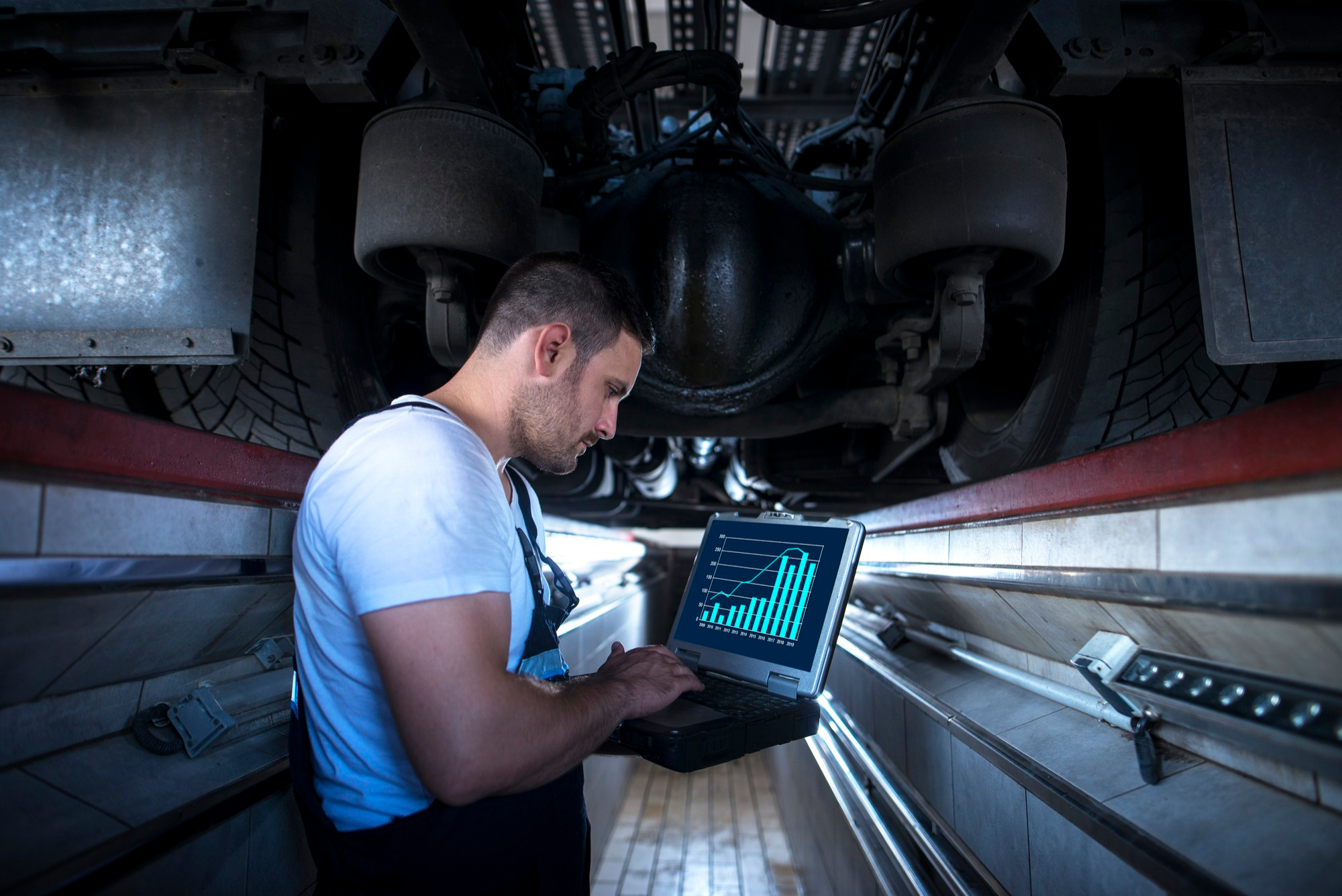 Expert mechanic checking for vehicle diagnostics on a laptop
